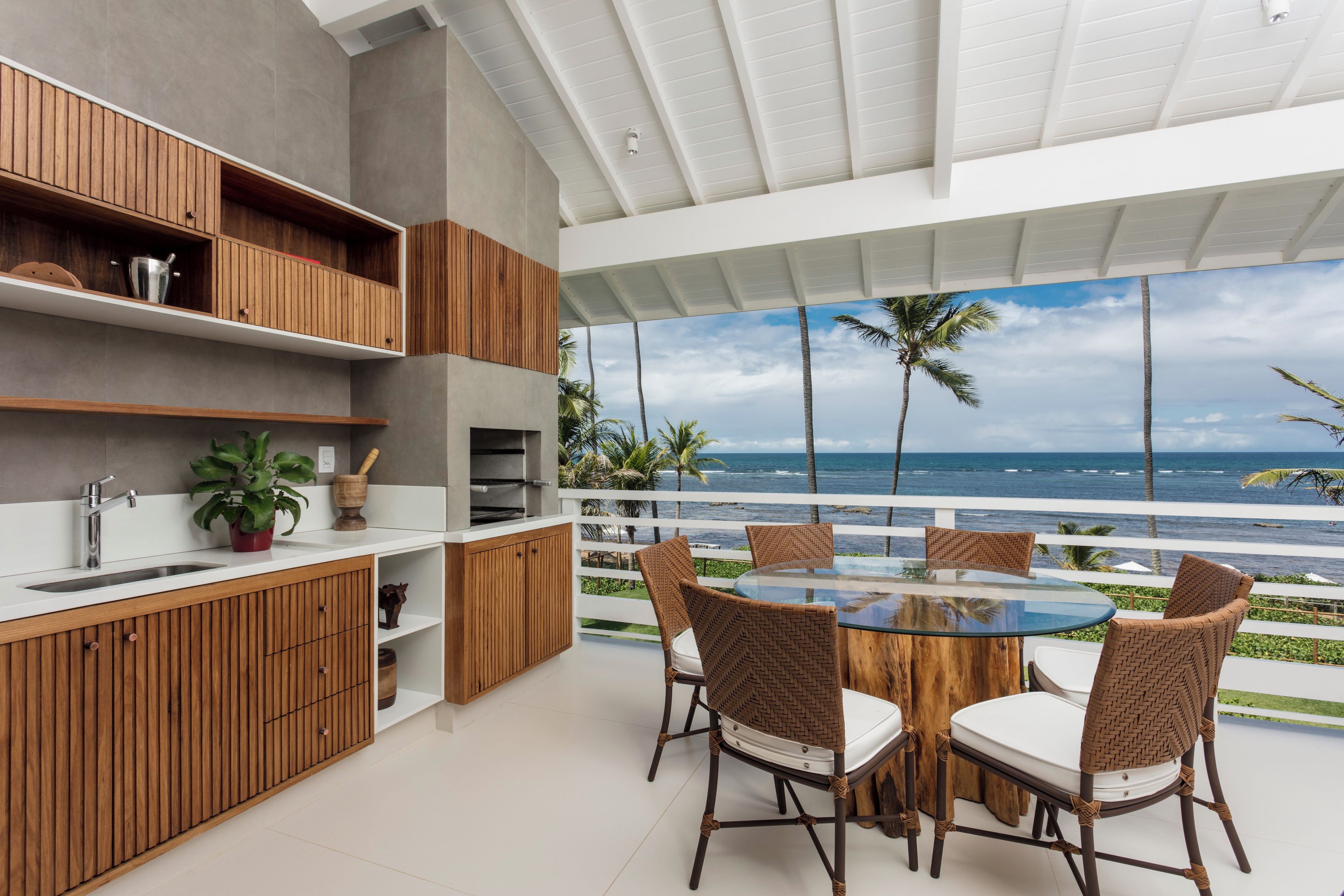 Een moderne keuken met houten kastjes en een inbouwoven, met uitzicht op een balkon en de oceaan.