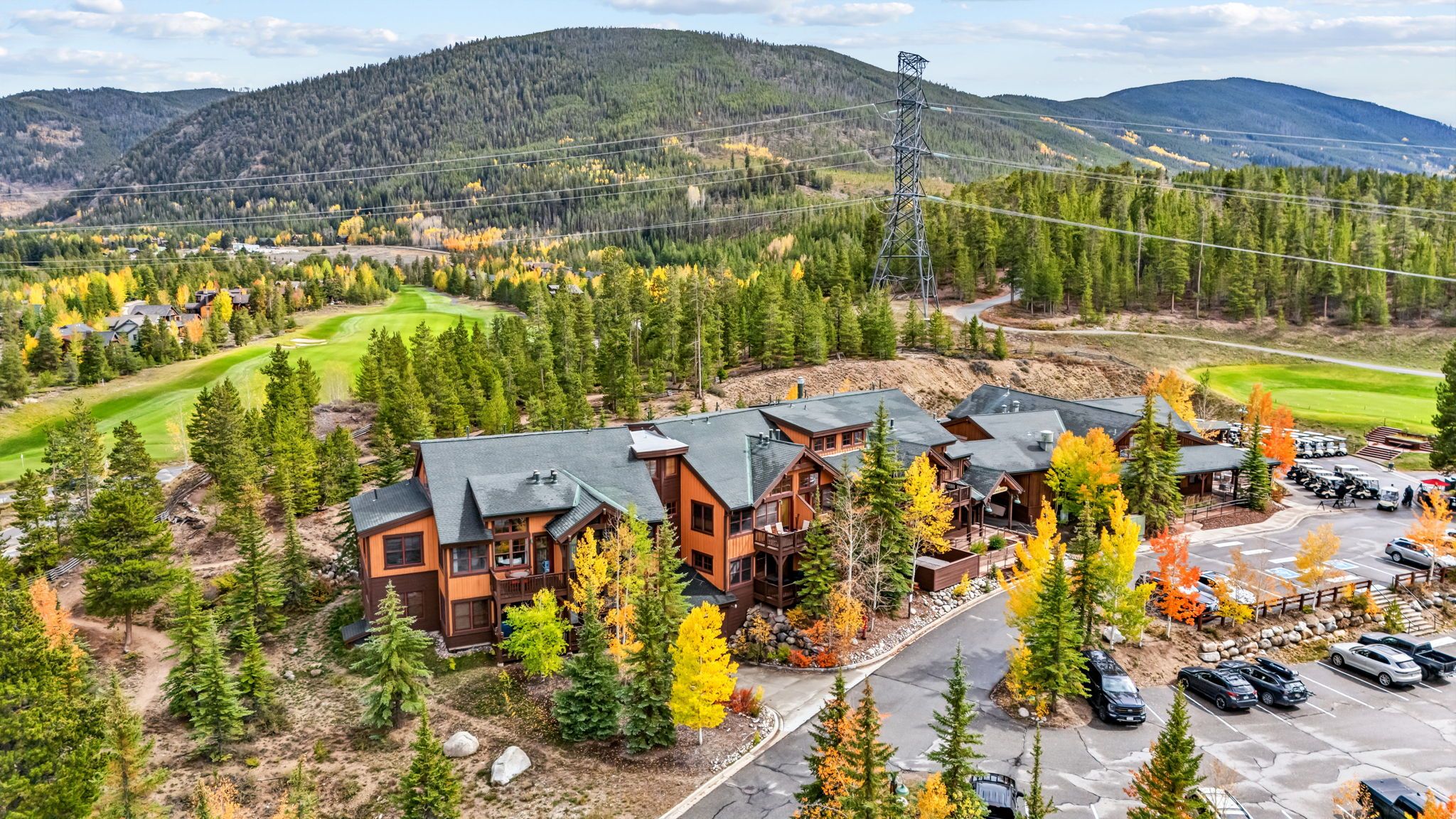 A lodge with multiple buildings, a parking area, and a golf course in the background.