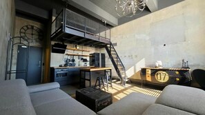 Un espace de vie de style loft comprenant un coin cuisine, un escalier et un canapé.