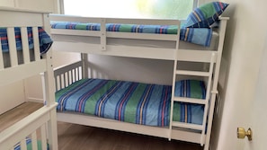 Een stapelbed met gestreept beddengoed en kussens.