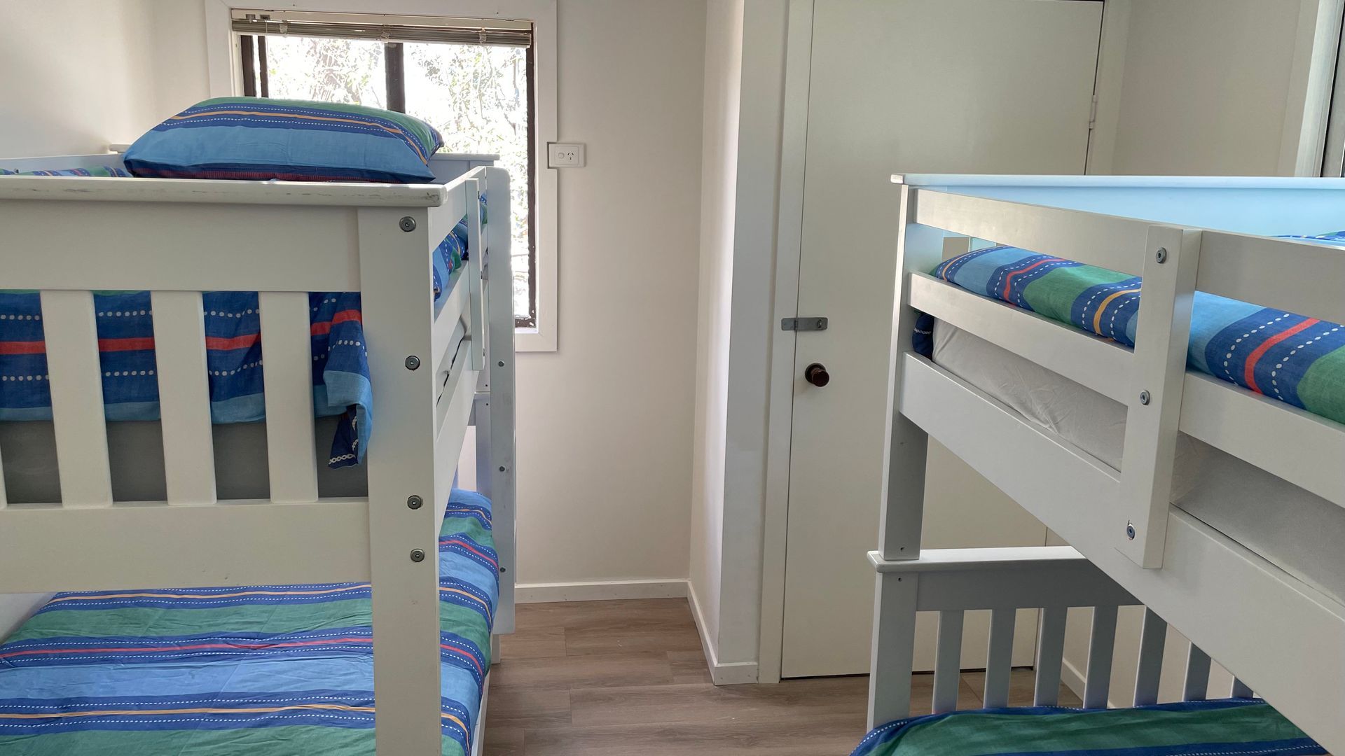 A room with two bunk beds, a door, and a window.