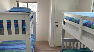 A room with two bunk beds, a door, and a window.