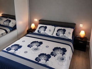 A neatly made bed with a floral pattern, two bedside lamps, and a mirror on the wall. - New Listing (Saint-Germain-de-Lusignan)
