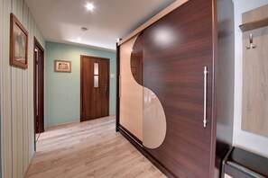 A hallway with wooden flooring, a wooden door, and a large wooden panel with a curved cutout. - RentPlanet - Apartamenty Wyszyńskiego (Świeradów-Zdrój)