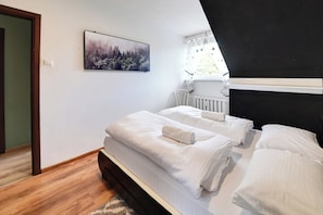 Een slaapkamer met twee bedden, een radiator, een raam met gordijnen en een ingelijst kunstwerk aan de muur.