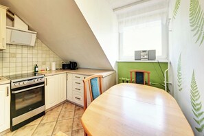 A kitchen with a stove, oven, and a dining table. - RentPlanet - Apartamenty Wyszyńskiego (Świeradów-Zdrój)