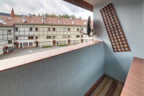 Een balkon met uitzicht op een rij traditionele gebouwen, een houten spijlenwerk muur en een schotelantenne.