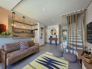 Ein moderner Wohnraum mit einer Couch, einem Teppich, einer Treppe mit Seildekoration und einer Küchenzeile.