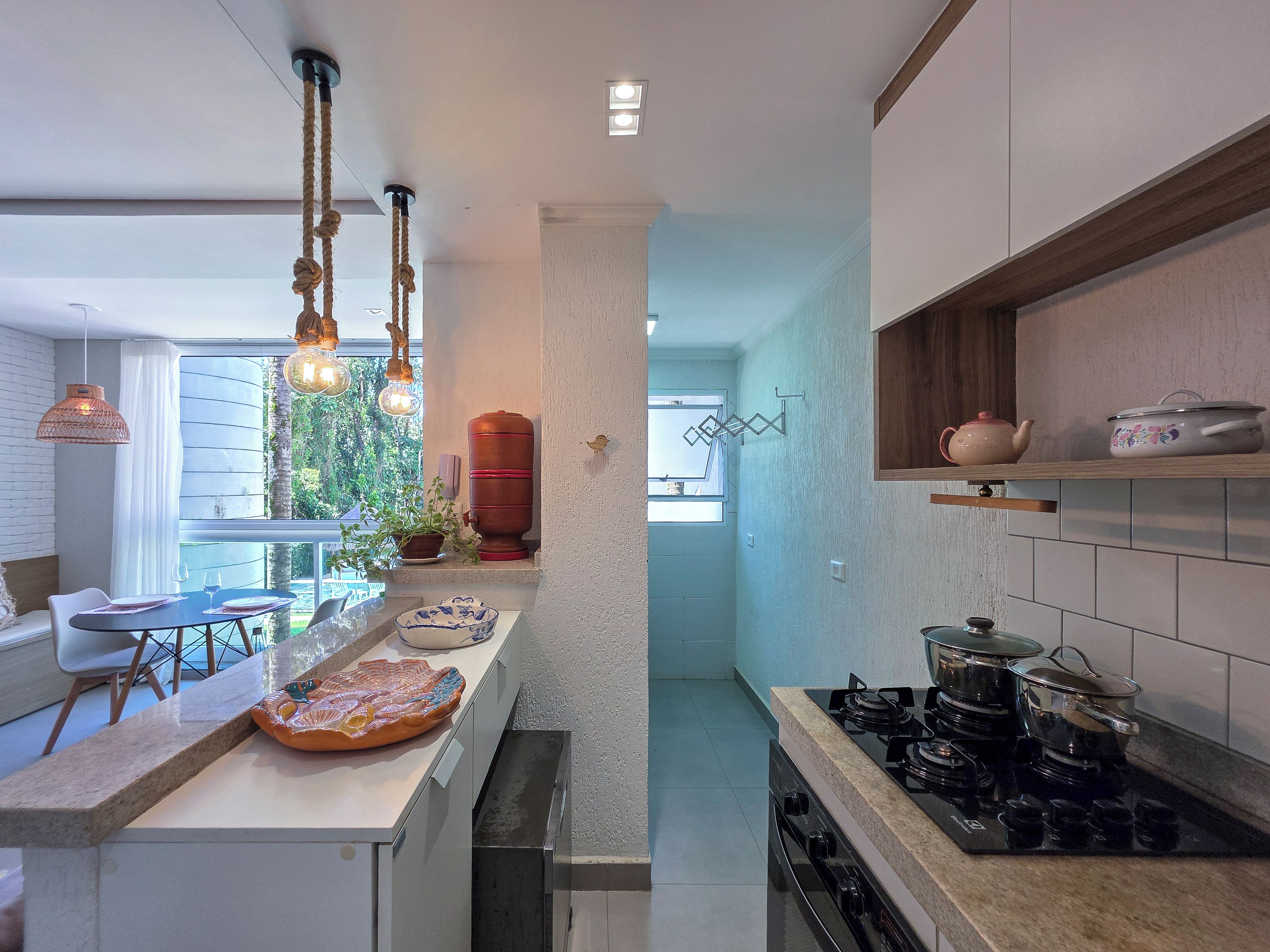 A modern kitchen with a gas stove, a sink, and a dining area with a table and chairs.