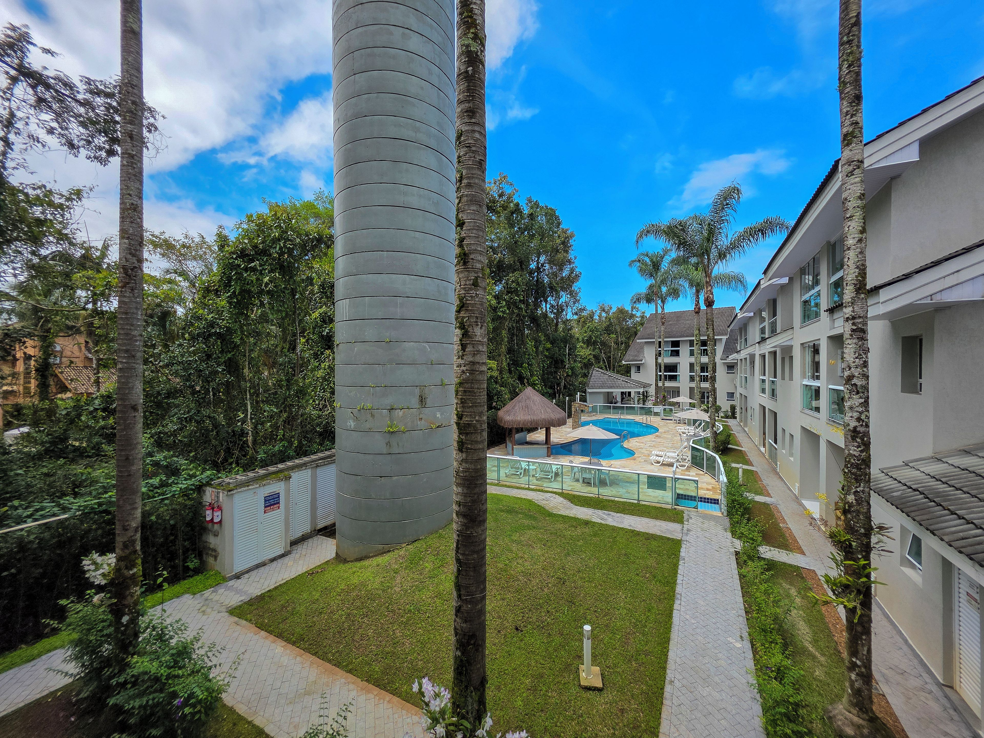 A hotel with a swimming pool, palm trees, and a large cylindrical structure.