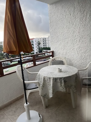A balcony with a table and chairs, a white textured wall, and a view of buildings and greenery. - 'Villasyaiza ' los Juncos I' (San Bartolomé de Tirajana)