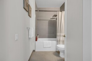 Uma casa de banho moderna com banheira, sanita e cortina de chuveiro.