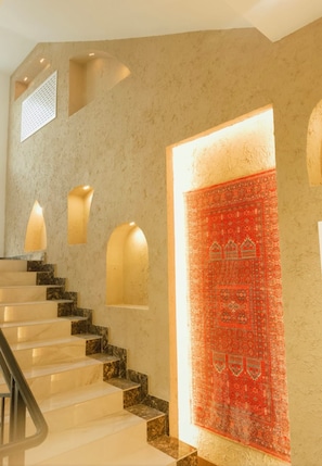 A staircase with marble steps and a red patterned wall.