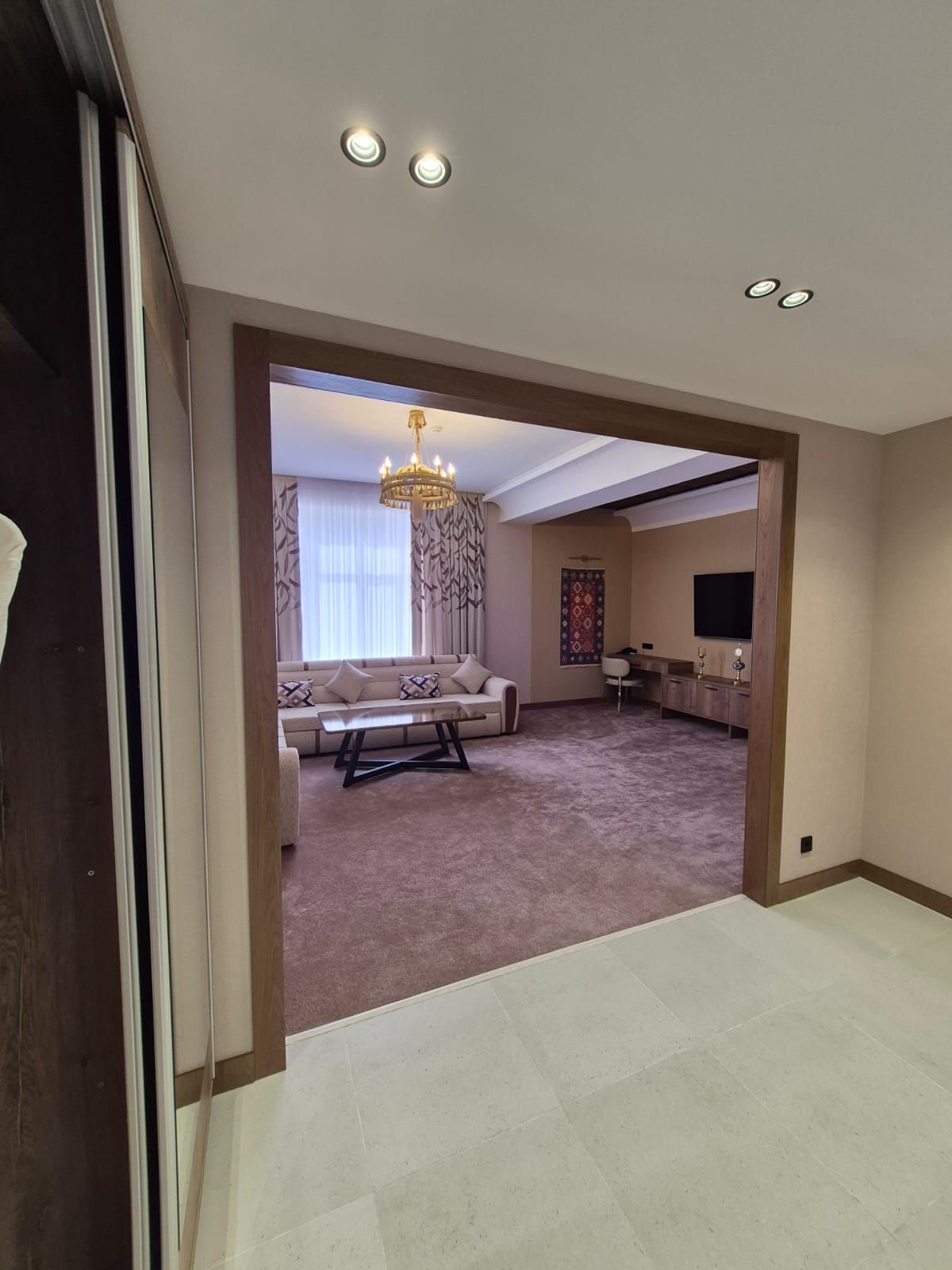 A spacious living room with a sofa, a coffee table, and a chandelier.
