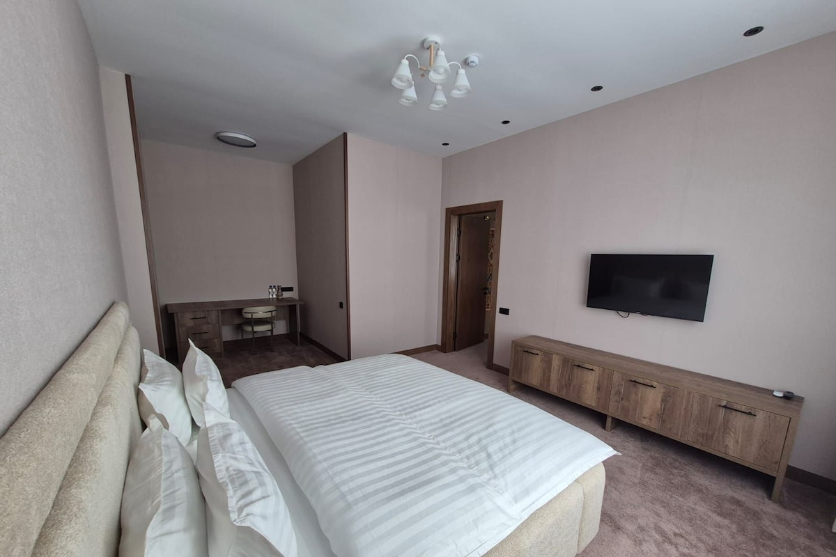 A bedroom with a bed, a TV, a desk, and a wardrobe.