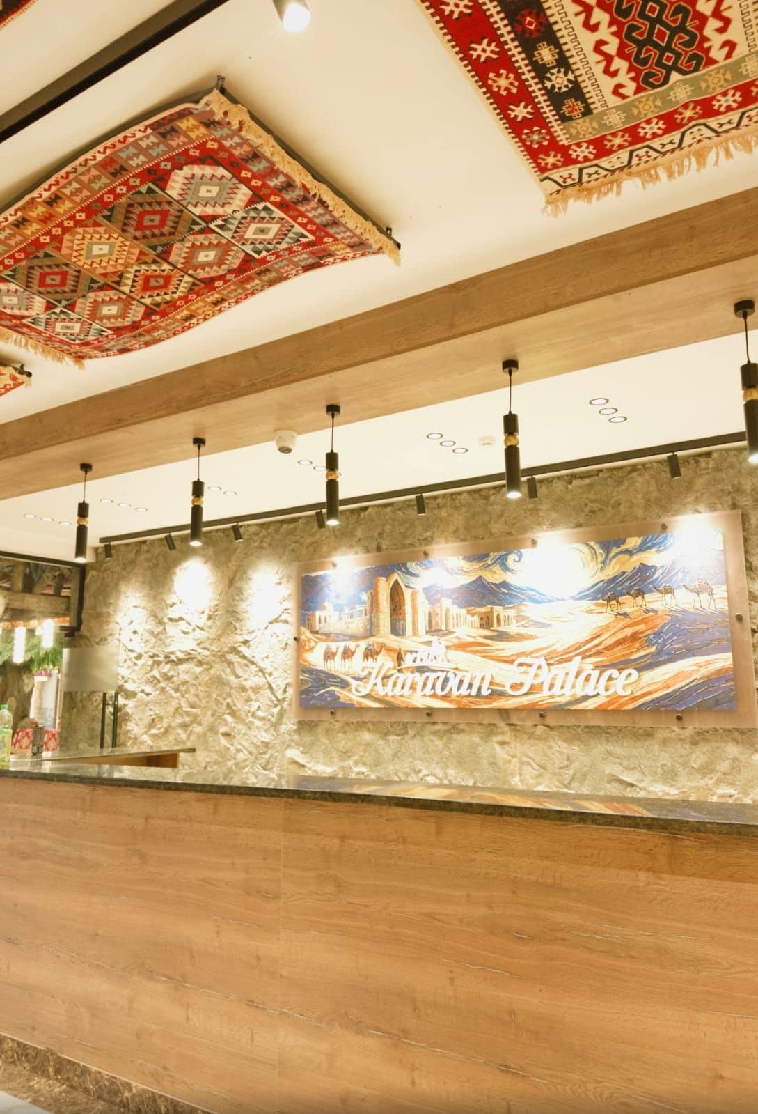 Una zona de recepción con una pared de piedra, un tapiz colgante y un cuadro enmarcado de un palacio.