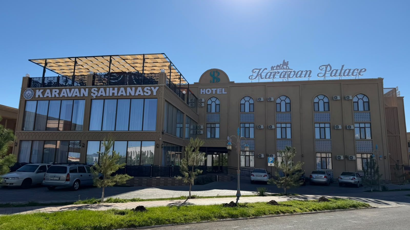 Un hotel con fachada moderna, amplias ventanas y un letrero que dice 'Karavan Palace Hotel'.