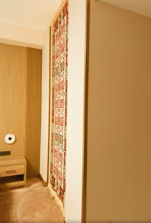 A room with a wooden door, a patterned tapestry, and a small wooden cabinet with a light.