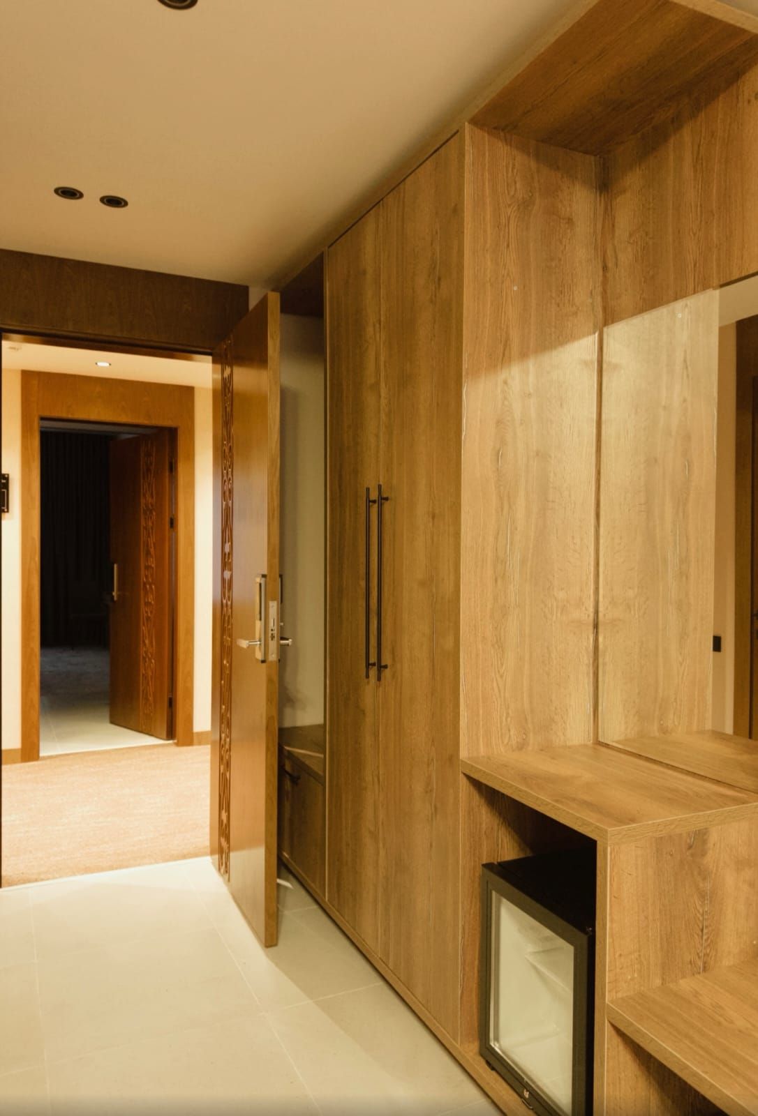Un corridoio con un'armadiatura in legno, una porta che dà su un'altra stanza e un televisore su un mobile.