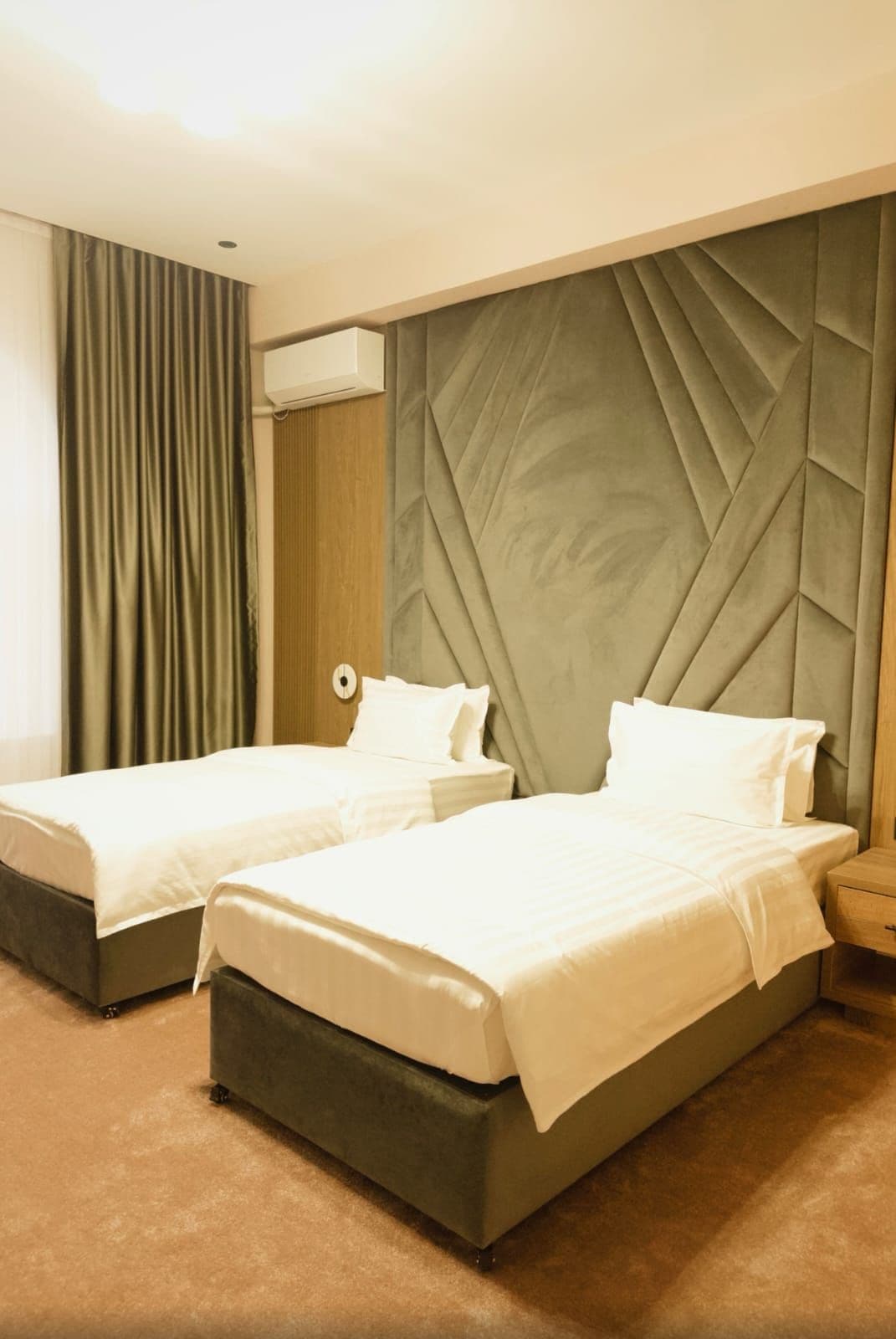 Una habitación de hotel con dos camas, un cabecero grande y acolchado y una pared de acento de madera.