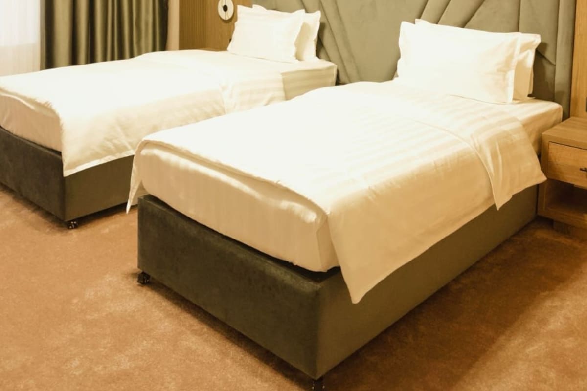 A hotel room with two beds, a large padded headboard, and a wooden accent wall.
