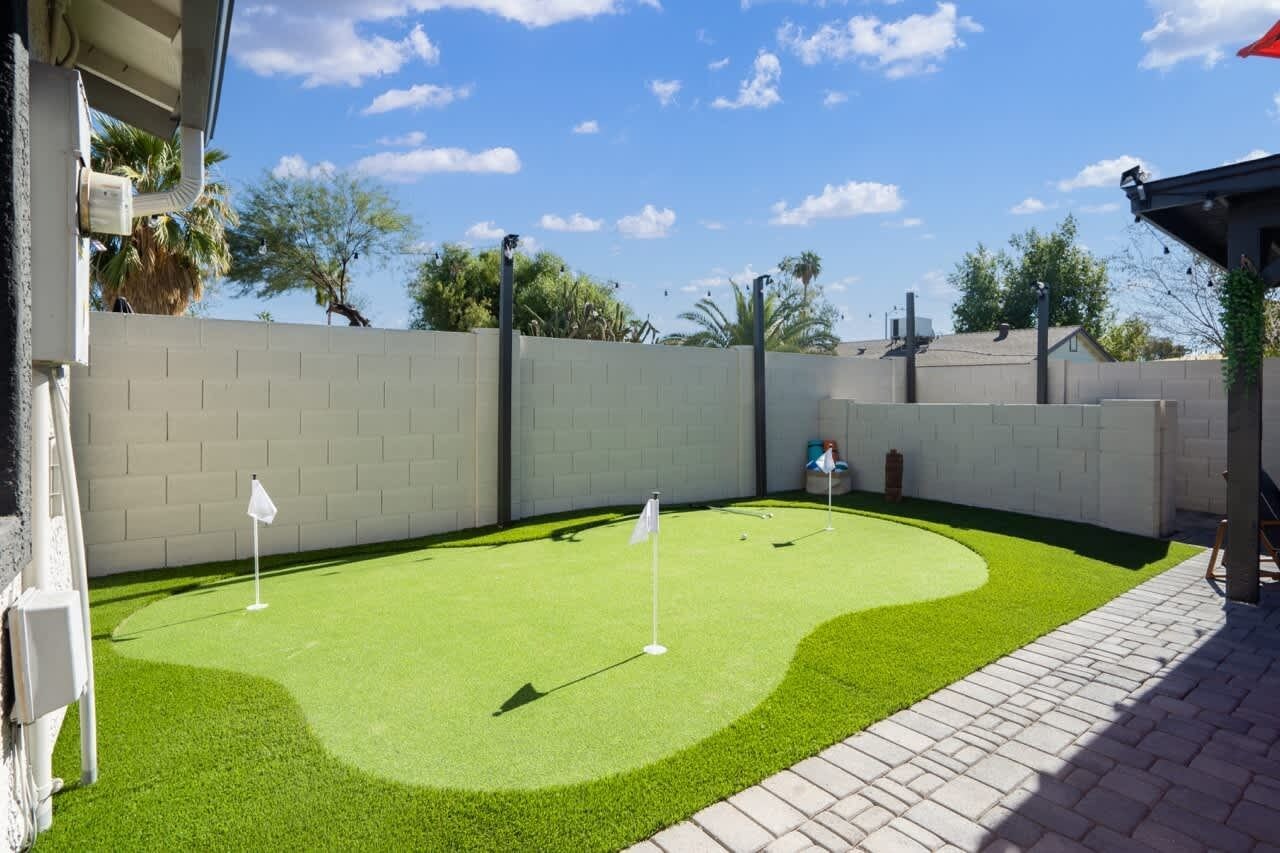 Un parcours de minigolf avec un mur en briques, une pelouse artificielle et deux drapeaux.