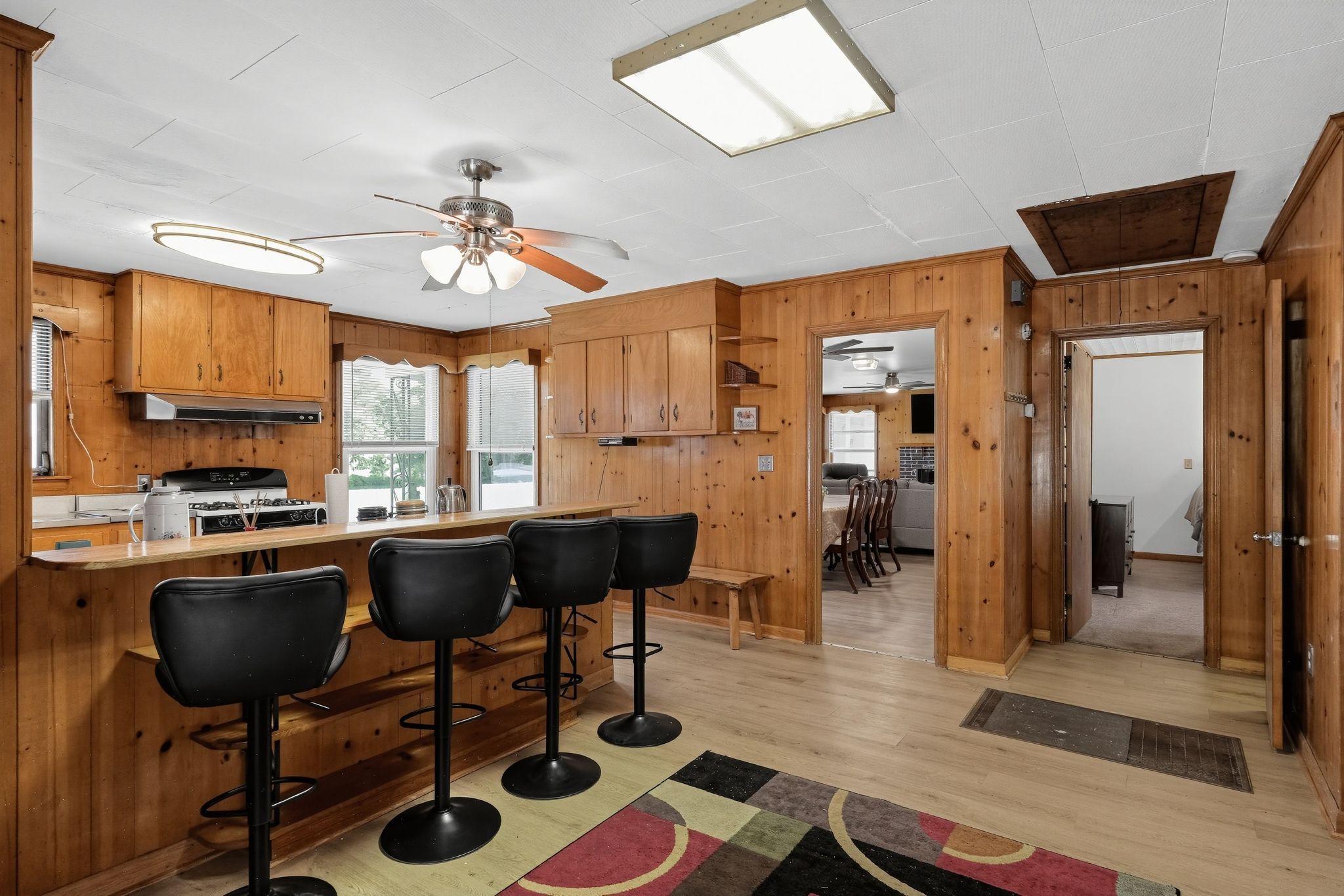 Kitchen with wood-paneled walls and a breakfast bar with black stools.