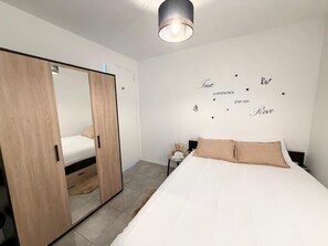 Un dormitorio con cama, armario, mesita de noche y una pared decorada con estrellas y texto.