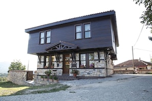 A two-story house with a stone facade, a porch with potted plants, and a view of the landscape. - TRULYA1881  (Kırklareli)
