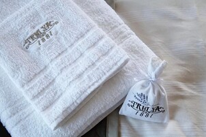 Neatly folded white towels with embroidered text and a tag, placed on a bed.