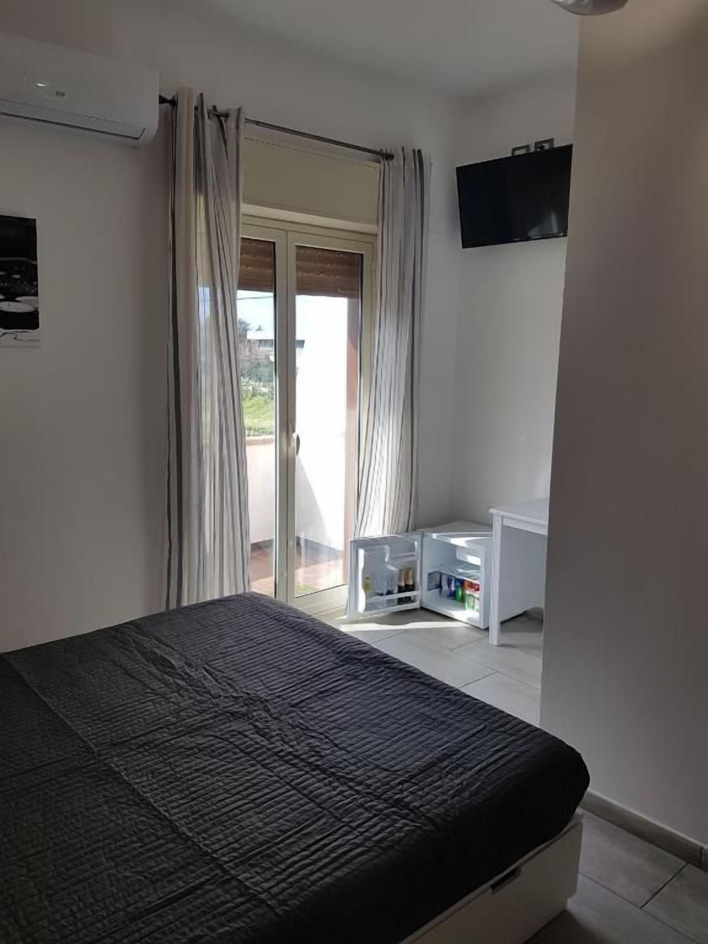 A bedroom with a bed, a desk, and a TV on the wall.