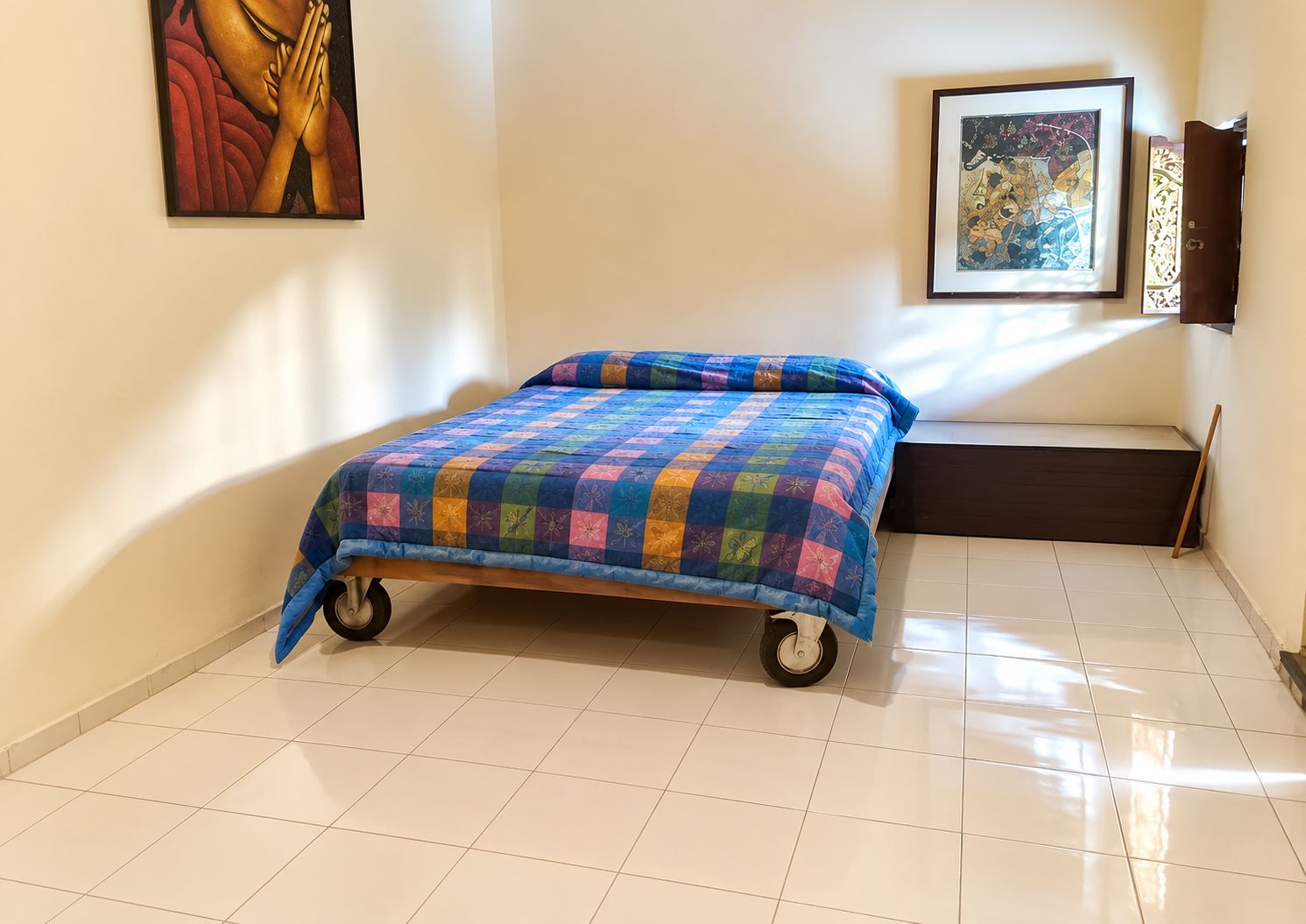 Een kamer met een bed op wielen, een ingelijst schilderij aan de muur en een bank tegen de muur.