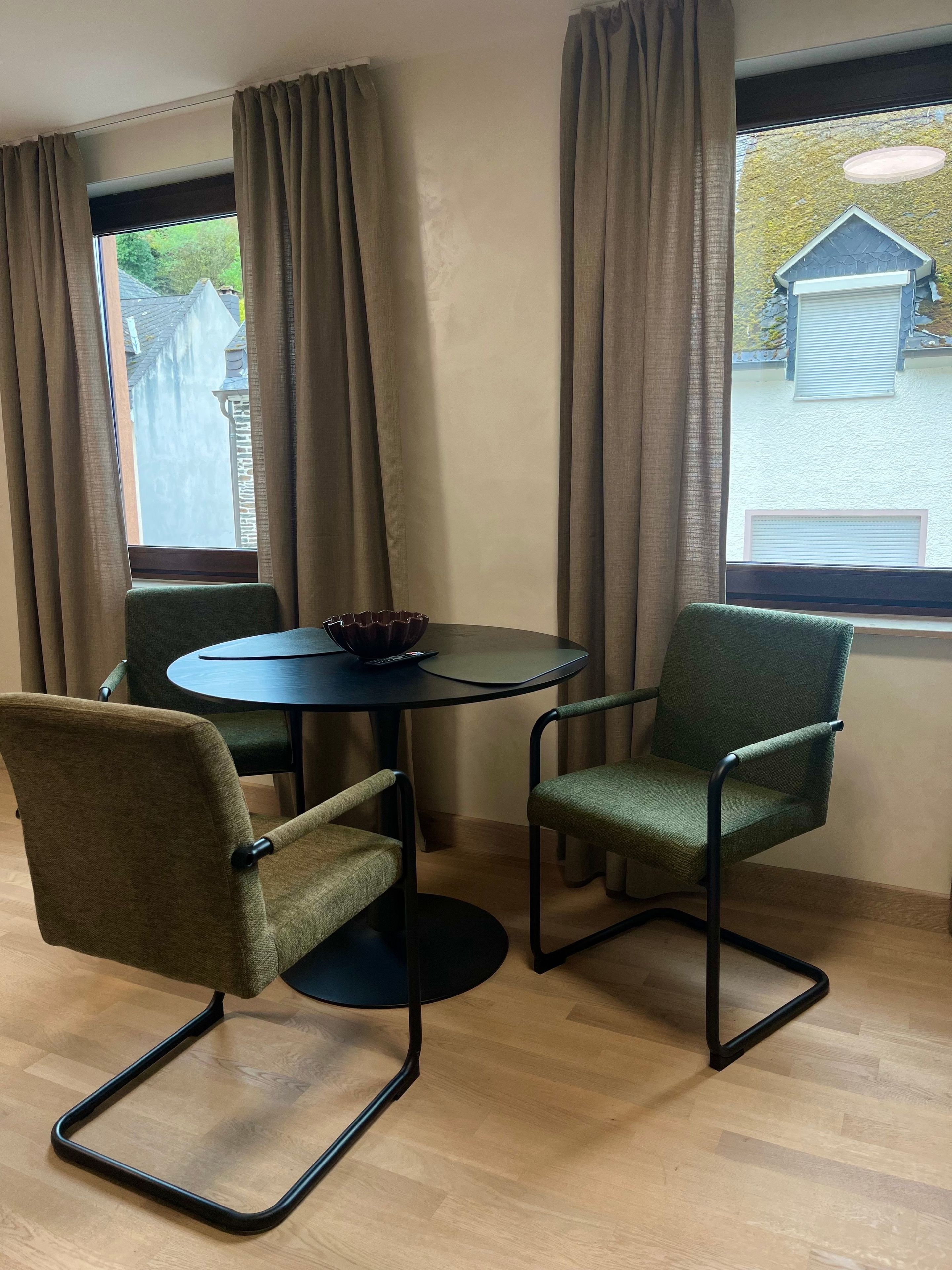Ein Zimmer mit einem runden Tisch, zwei Stühlen, einer Fernbedienung und einer Schüssel auf dem Tisch.