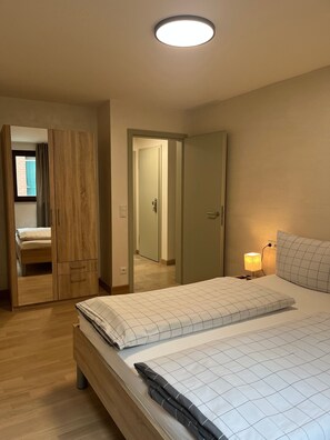 Ein Schlafzimmer mit Bett, Nachttisch, Lampe, Kleiderschrank und Spiegel.