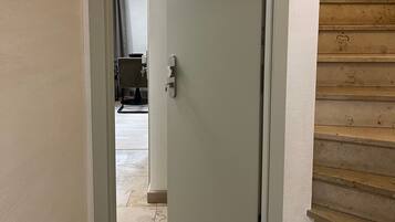 Un couloir mène à une porte portant le numéro 1, avec un escalier sur la droite.