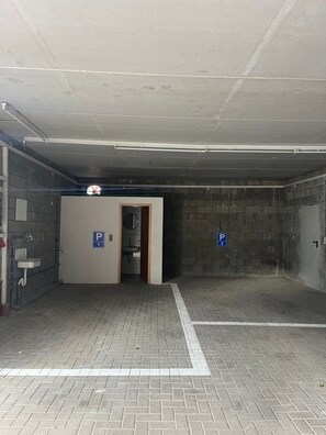 Un garage avec deux places de stationnement délimitées, un évier et une porte donnant accès à des toilettes.