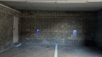 Eine Parkgarage mit Ziegelwänden und Fliesenboden, mit Parkplätzen, die mit den Nummern 3 und 4 gekennzeichnet sind.
