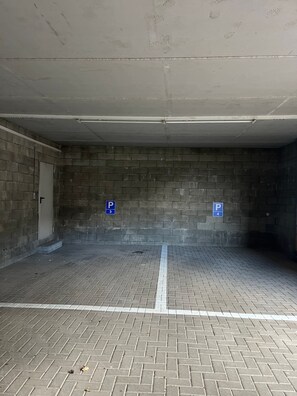 Eine Parkgarage mit Ziegelwänden und Fliesenboden, mit Parkplätzen, die mit den Nummern 3 und 4 gekennzeichnet sind.