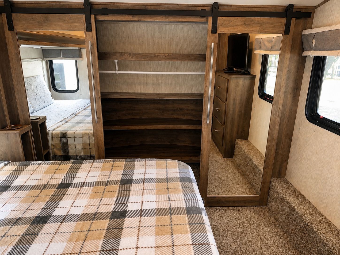 Interni di un camper compatto con un letto, un vano portaoggetti e un piccolo angolo salotto.