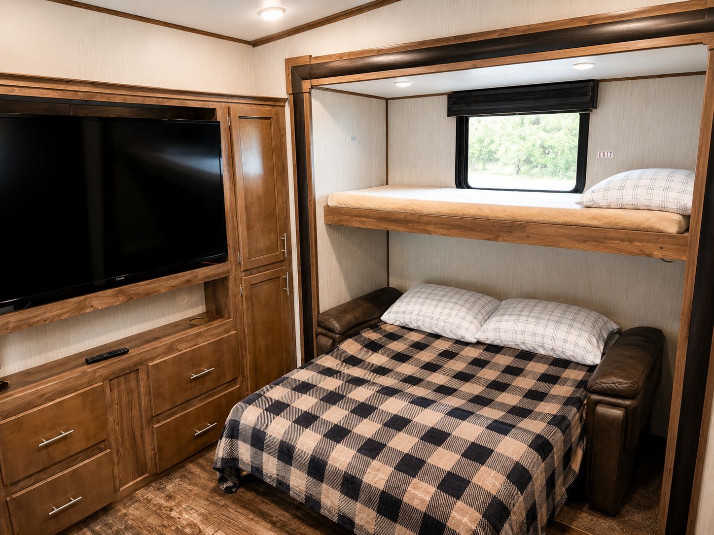 Interior compacto de una caravana con televisión, litera y una pequeña zona de estar.