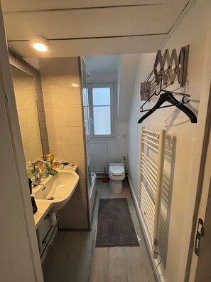 Un baño pequeño con lavamanos, espejo y retrete.