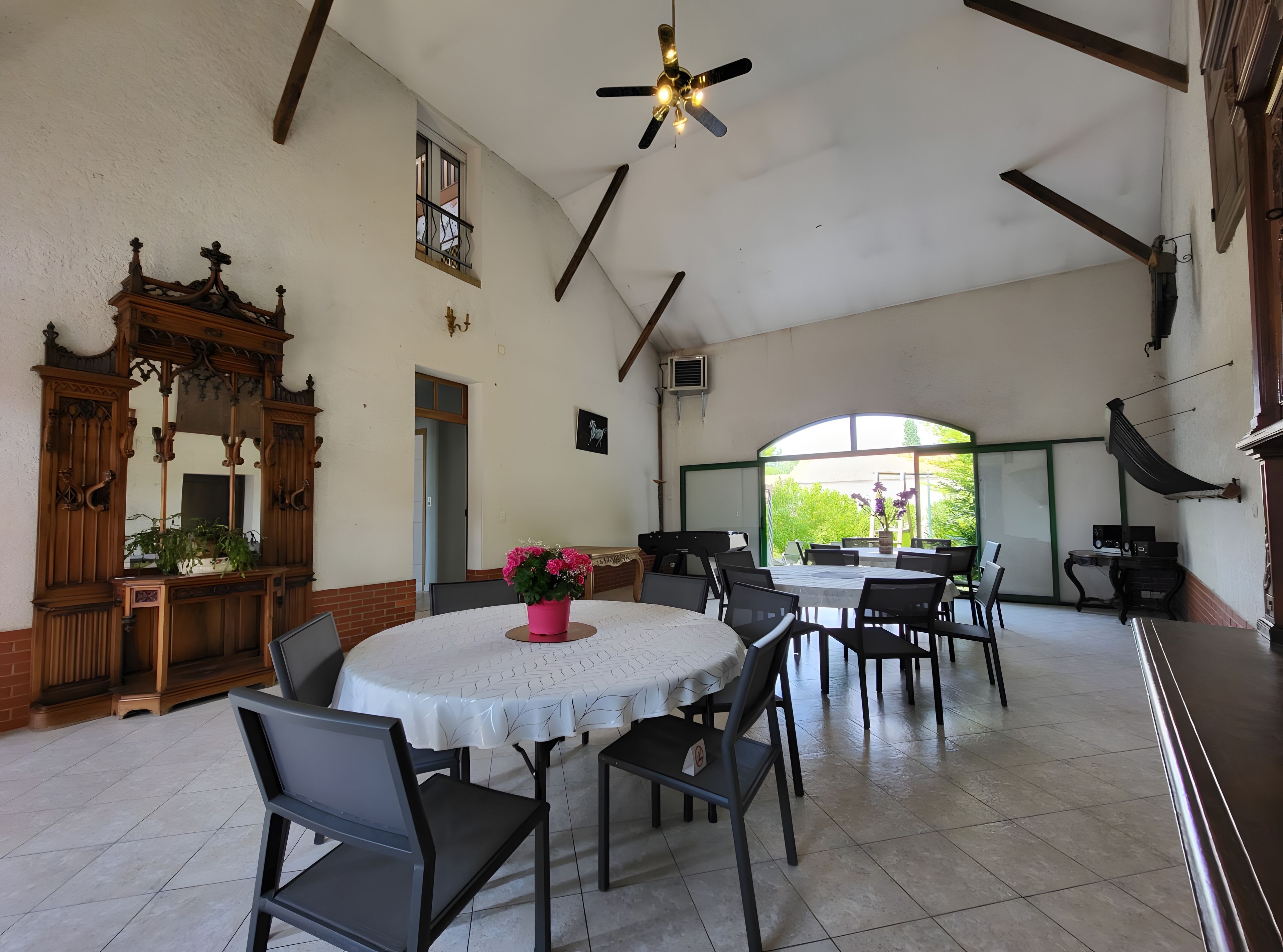 A dining area with a round table, chairs, and a ceiling fan.