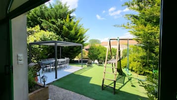 A patio with a table and chairs, a swing set, and a pergola.