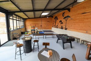 Sala de lleure amb taula de futbolí, taula de bitlles i diferents zones d'aixecament.