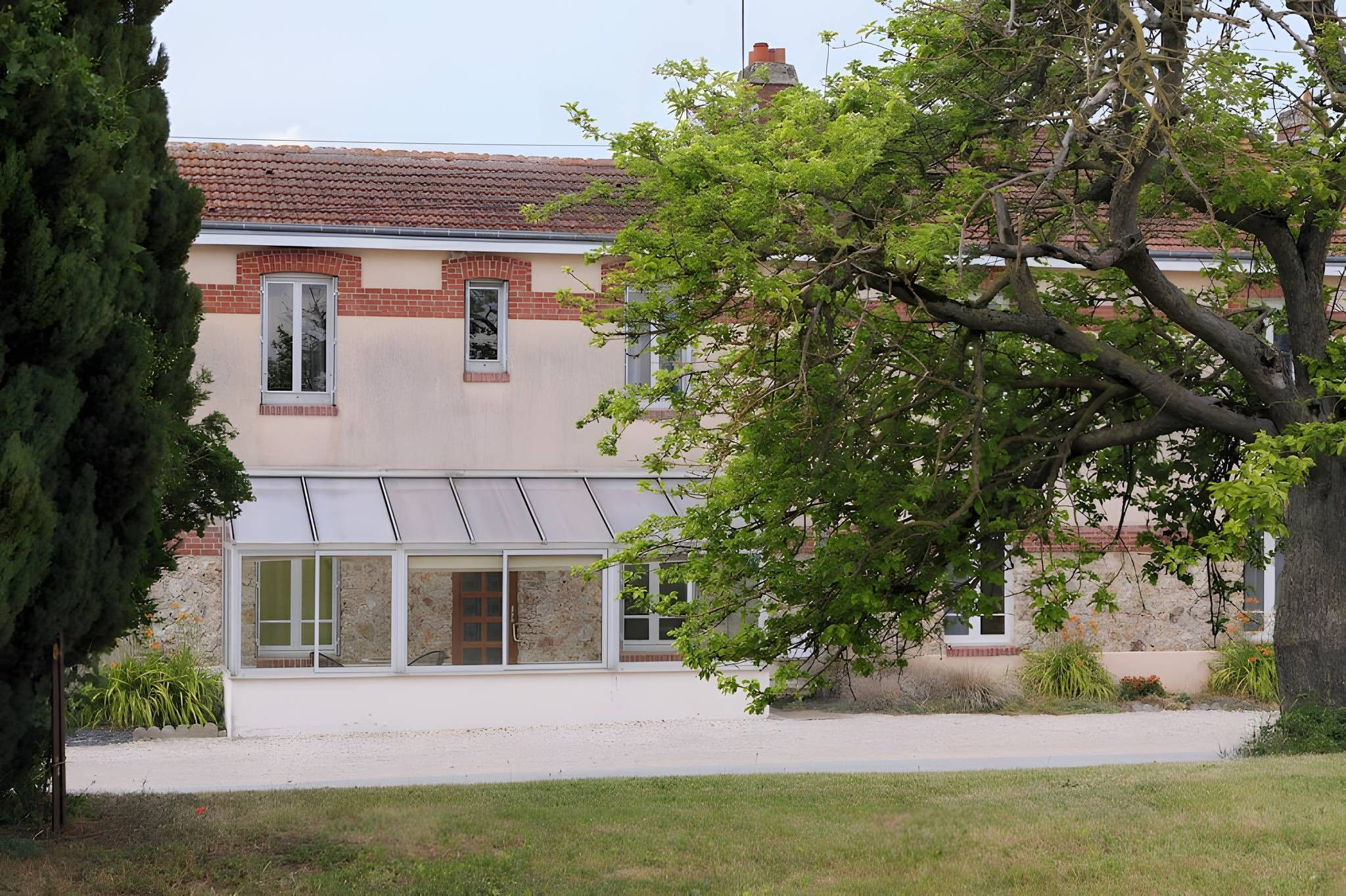 A building with a brick facade, large windows, and a tree in the foreground.