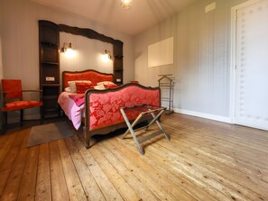 A bedroom with a wooden floor, a bed with a red headboard, a chair, and a bedside table. - Holiday Home 'Ferme De Saint-rémy, En Champagne' with Private Terrace, Wi-Fi and Air Conditioning (Saint-Remy-le-Petit)