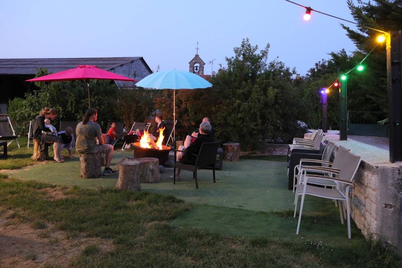 An outdoor seating area with a fire pit, chairs, and umbrellas.
