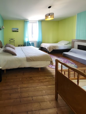 Un dormitori amb dos llits, un paviment de fusta, una làmpada penjant i una finestra amb cortines.