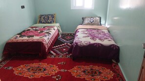 Habitación con dos camas, cada una con cubrecama floral, un tapete estampado y una ventana con luz natural.