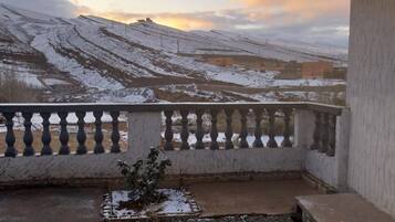Varanda com vista para montanhas cobertas de neve e um céu nublado.